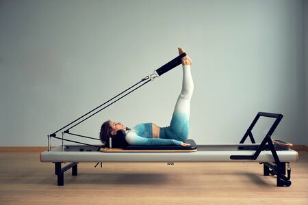 young asian woman pilates stretching sport in reformer bed instructor girl in a studioの写真素材