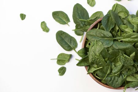 Fresh spinach in a wooden bowl isolated on white background.の写真素材