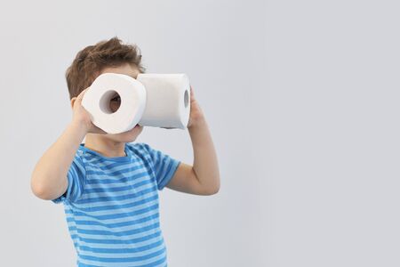 Active boy playing with toilet paper in retro filter,kid boy looking through toilet roll,Child holding two white tissue, looking through toilet paper like binocularsの写真素材