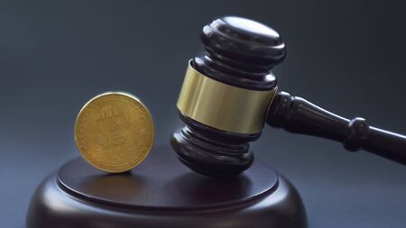 Crypto currency law theme, gavel and bitcoin symbol on brown table with copyspaceの写真素材