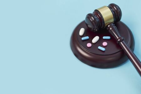 Wooden judge gavel with drugs on table. Space for text. Medical concept. on a blue background. expired drugs. fake market.の写真素材