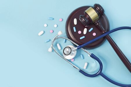 brown gavel and a medical stethoscope on blue background. symbol photo for bungling and medical error.の写真素材