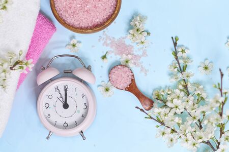 Spa setting spring flowers with towel ,salt in bowl, Spring Time Change, Spring flowers and Alarm Clock.の写真素材