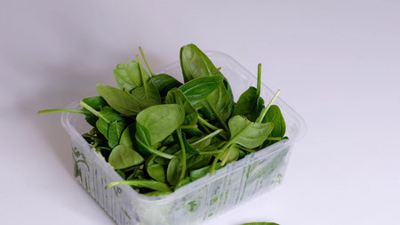 Woman using food film for food storage on a white table. Roll of transparent polyethylene food film...