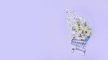 flowers fly out of the shopping cart on a blue background. spring shopping concept. seasonal sale.の写真素材