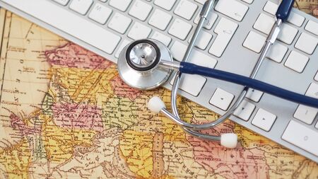 Keyboard, medical stethoscope and a protective mask on a geographical map. Concept stay home and remote work. medicine, hospital, safety, epidemic, doctors call, online, consultation. Banner.の写真素材