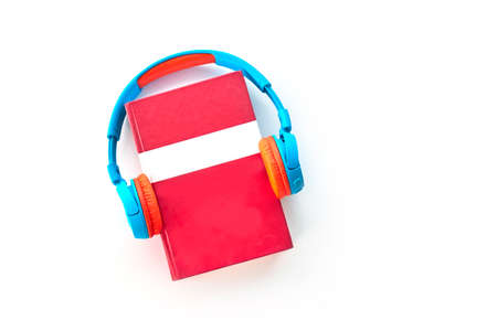 Audio book concept. Headphones and red book Top view with space for your text. Flat lay, top view, copy spaceの写真素材