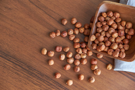 Hazelnut kernels and whole hazelnuts on old brown table, selective focus.
