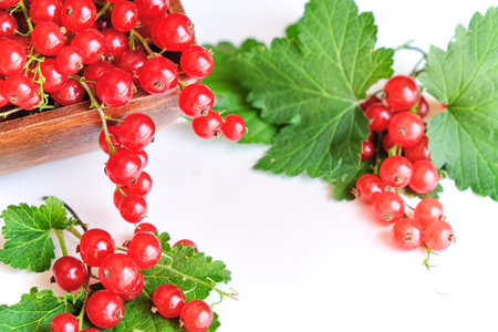 fresh red currant in a wooden bowl isolated on white background. summer harvest of vitamins.