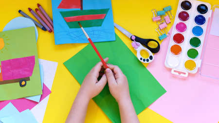 School supplies, stationery on yellow background - space for caption. Child ready to draw with pencils and make application of colored paper. Top view.の写真素材