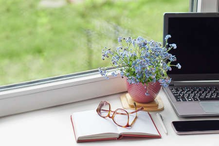 Workplace near the window with computer. Copy space. Modern laptop on desk near window at home. Morning time with warm light. working desk with a cup of coffee. business concept.の写真素材
