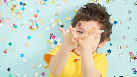 happy birthday child. Photo of charming cute fascinating nice little boy blowing confetti at you to show her festive mood with emotional face expression.の写真素材
