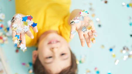 happy birthday child. Photo of charming cute fascinating nice little boy blowing confetti at you to show her festive mood with emotional face expression.の写真素材