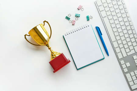 Stylish minimalistic workplace with keyboard, notebook, trophy, notebook, in flat lay style. White background. copy space, flat lay, top view, mock upの写真素材