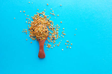 Bee pollen in a wooden spoon healthy food supplements. blue table background. ball or pellet of field-gathered flower pollen packed by worker honeybeesの写真素材