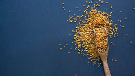 Bee pollen in a wooden spoon healthy food supplements. Close up on a black background. Top view, flat lay. copy space for text.の写真素材