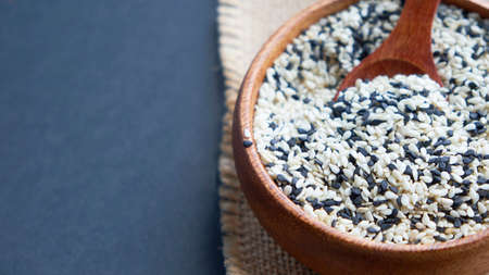 Organic natural sesame seeds wooden spoon. toasted sesame seeds. Raw, whole, unprocessed. Natural light. Selective focus. Close up on a black background. Top view, flat lay. copy space for text.の写真素材