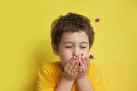 happy birthday child. Photo of charming cute fascinating nice little boy blowing confetti at you to show her festive mood with emotional face expression.の写真素材