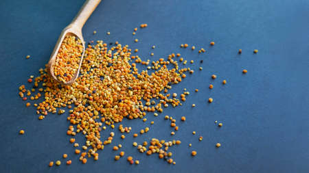 Bee pollen in a wooden spoon healthy food supplements. Close up on a black background. Top view, flat lay. copy space for text.の写真素材