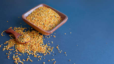Bee pollen in a wooden spoon healthy food supplements. dark table background. ball or pellet of field-gathered flower pollen packed by worker honeybeesの写真素材