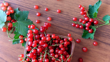 wet red currant on brown wooden table.