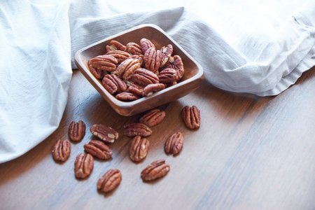 pecan nuts in wood bowl on old brown table, selective focus. top view. Healthy food and snack.