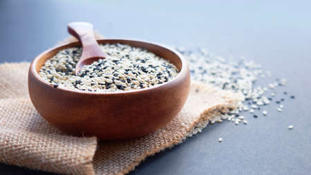 Organic natural sesame seeds wooden spoon. toasted sesame seeds. Raw, whole, unprocessed. Natural light. Selective focus. Close up on a black background. Top view, flat lay. copy space for text.の写真素材