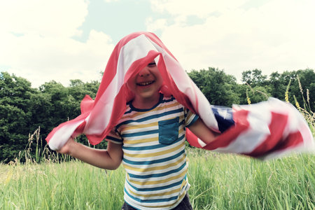 Patriotic holiday.Young boy with American flag.USA celebrate 4th of July.の写真素材