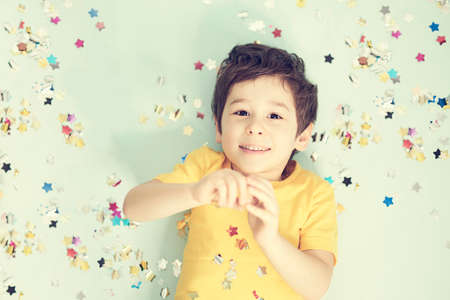 happy birthday child. Photo of charming cute fascinating nice little boy blowing confetti at you to show her festive mood with emotional face expression.の写真素材