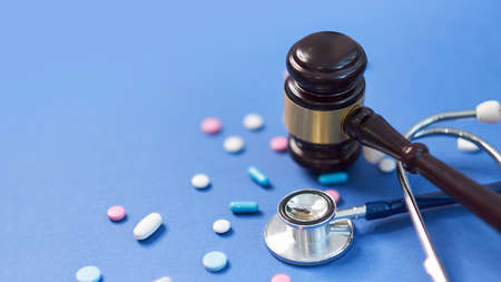 Wooden judge gavel with drugs on table. Space for text. Medical concept. on a blue background. expired drugs. fake market.の写真素材