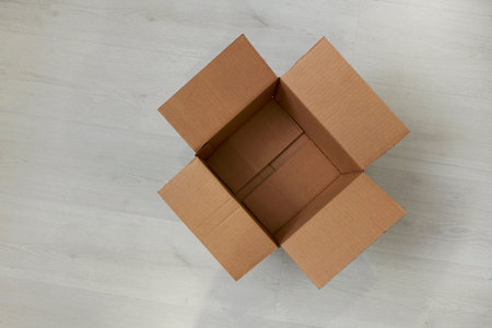 Flat lay of empty open cardboard box on wooden surface