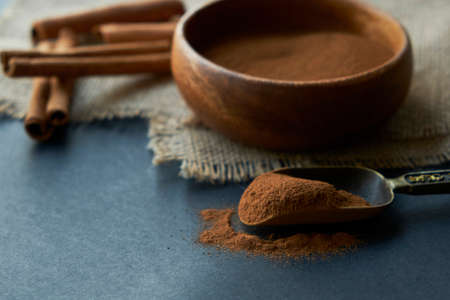 cinnamon sticks, tied with jute rope in rustic style. Ground cinnamon in a wooden bowl and vintage scoop. Close up on a black background. copy space for text. side view, flat lay.の写真素材