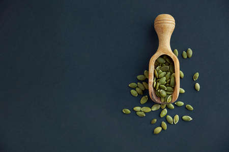 pumpkin seeds in a wooden bowl and vintage scoop. Close up on a black background. copy space for textの写真素材