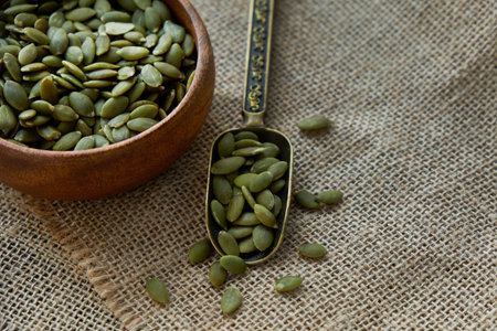 pumpkin seeds in a wooden bowl and vintage scoop. Close up on a black background. copy space for...