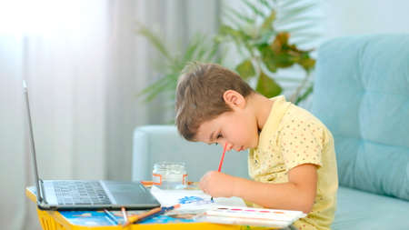 little cute boy draws with pencils. the child is engaged in creativity at homeの写真素材