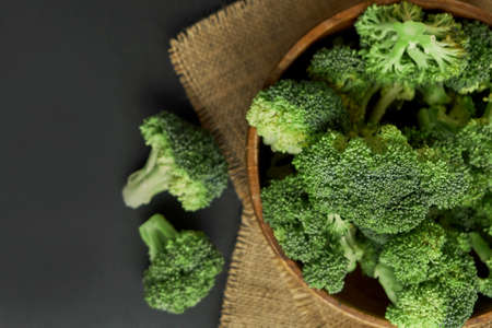 Fresh Broccoli in wooden bowl and seed oil in rustic style. Close up on a black background. copy space for text. Top view, flat lay.の写真素材