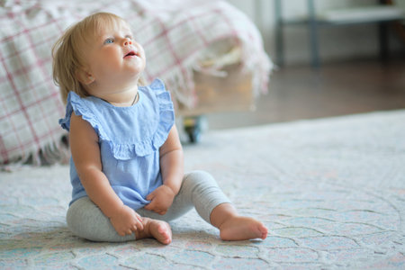 childhood, babyhood and people concept. happy little baby girl sitting on carpet at home.
