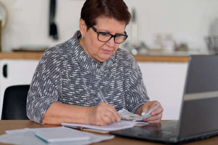 Old people, tax return and home banking. Worried senior lady paying federal taxes, doing family budget. Elderly hispanic person and stress. Concept of money, finance, financial problemsの写真素材