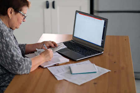 Old people, tax return and home banking. Worried senior lady paying federal taxes, doing family budget. Elderly hispanic person and stress. Concept of money, finance, financial problemsの写真素材
