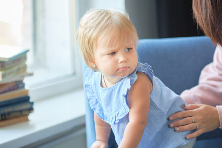 Portrait of a pretty little baby girl in a blue dress. cute blonde babe in the living room