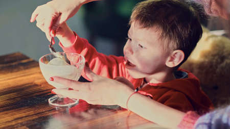 Little boy eating ice cream in cafe. Cute child, enjoying vanilla yogurt in a restaurantの写真素材
