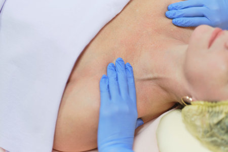 Close up portrait of charming woman with closed eyes enjoying skincare procedure. Masseuse arms...