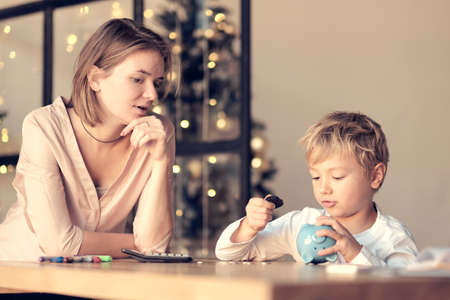 Mother and child putting coin into piggy bank. Education of children in financial literacy. Money, cash, investment.の写真素材