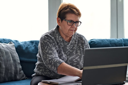 Senior woman using laptop for websurfing. The concept of senior employment, social security. Mature...