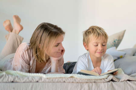 Mom teach son reading a book is on the bed at home. Education Concepts. Pastel colors, selective focus.の写真素材