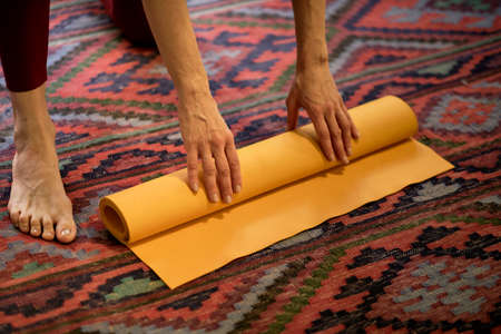 Woman rolling her mat after a yoga classの写真素材