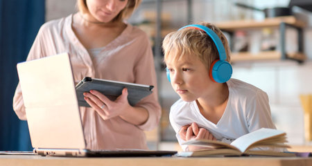 mom helping young son with laptop to do homework. Young woman teaching little boy to use the...