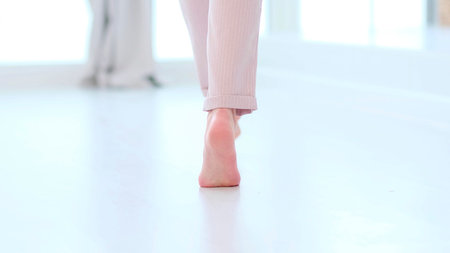 Side close up view of unrecognizable woman feet legs, barefoot girl standing indoors inside of modern home enjoy warm wooden heated floor. soft focusの写真素材