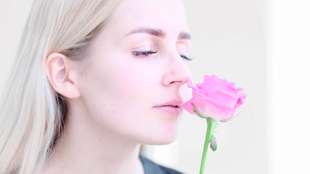 Beautiful young woman with delicate rose flower. Girl clean fresh skin touching her face in flowers. soft focus, selective focusの写真素材