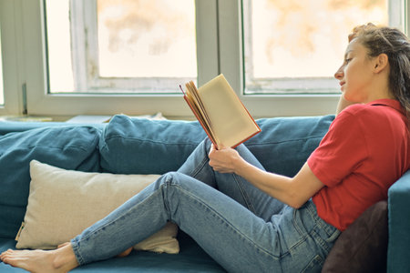 middle aged woman writing in notebook on sofa at home. beautiful woman at home writing and working with diary. Girl at home.の写真素材